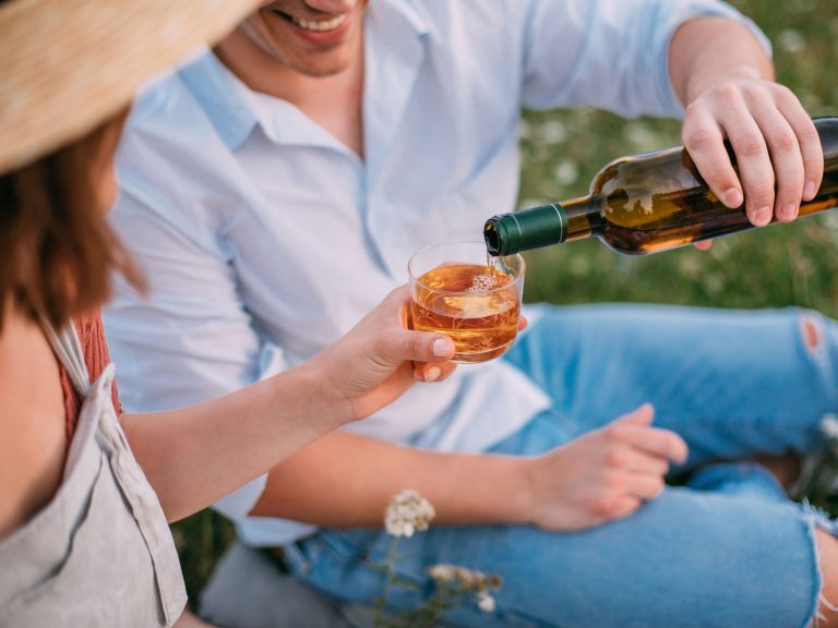 Man pouring drink for woman