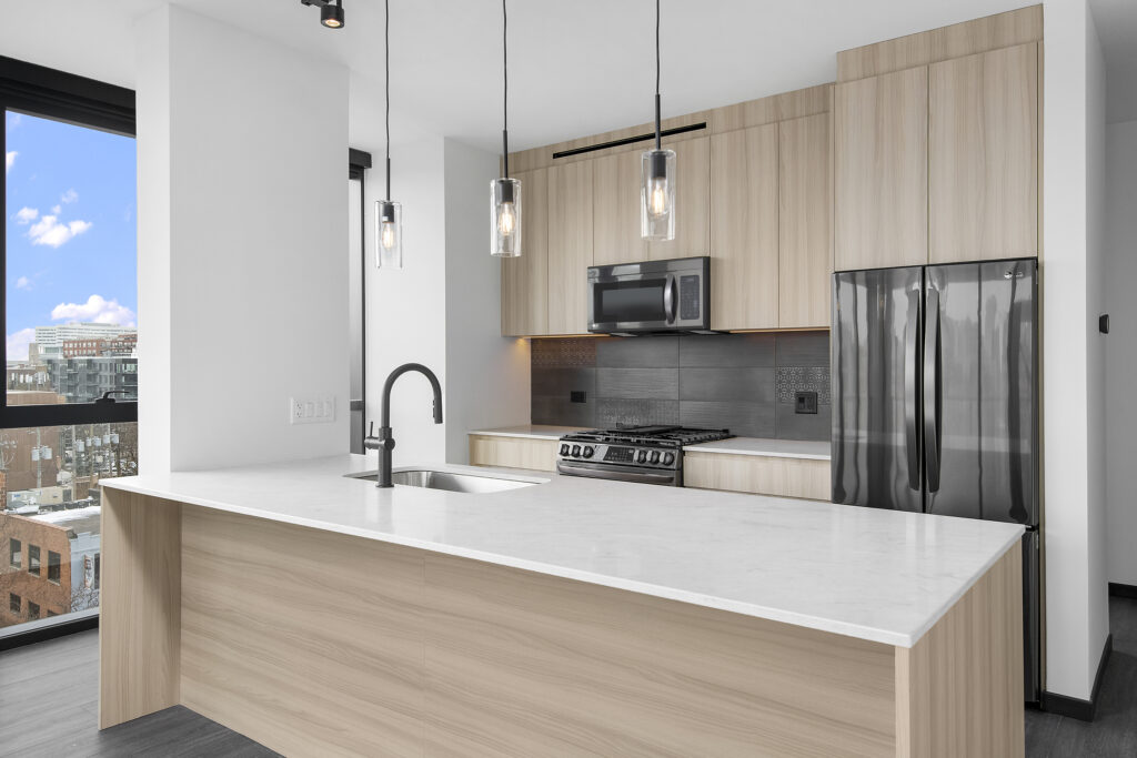 modern kitchen featuring a large island, pendant lighting, and stainless steel appliances at Parq Fulton